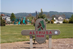 Cross-Shaped Sign Reading Altrusa Park with a Playground Structure in the Distance